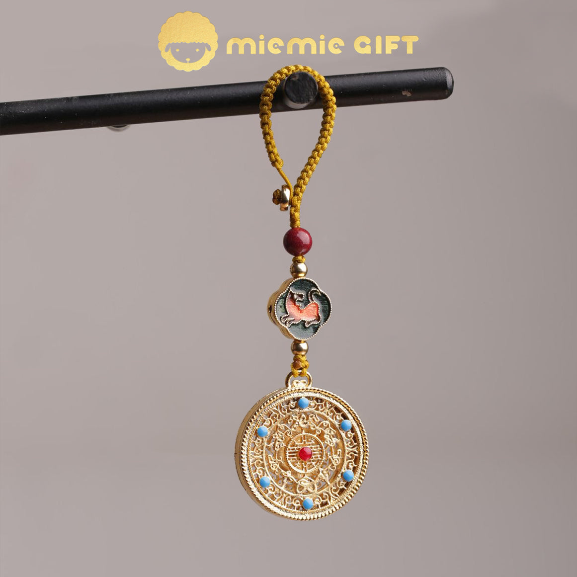 A 12 Zodiac Lucky Charm Pendant hanging from a handcrafted braided cord. Features a golden alloy spinning disk with intricate details, a colorful zodiac symbol, faux cinnabar bead, and elegant design. A meaningful accessory to bring luck and prosperity.