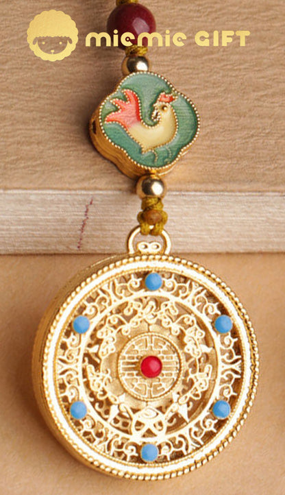 Close-up of the front design of the 12 Zodiac Lucky Charm Pendant, featuring an intricate golden spinning disk with blue accents, a vibrant rooster zodiac emblem, and a faux cinnabar bead. A beautifully crafted accessory to bring luck and prosperity.