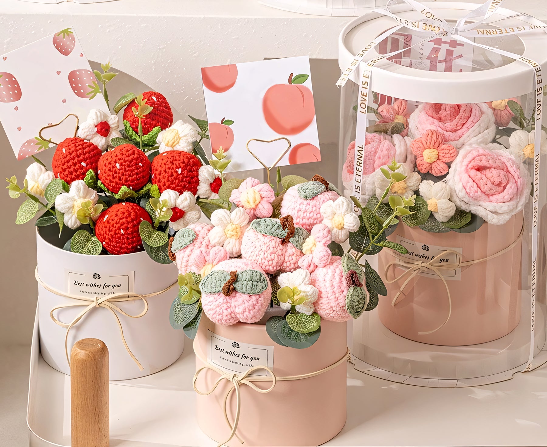 Beautiful handmade crochet flower gift sets, featuring red strawberries, pink roses, and peach-themed designs in elegant boxes, ideal for heartfelt gifting.

