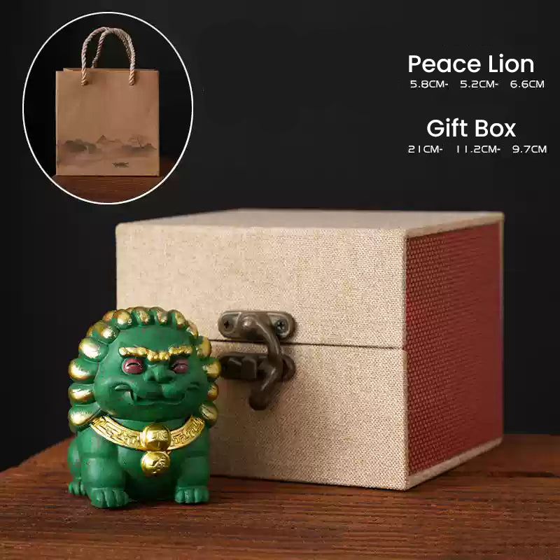 A green Peace Lion ornament with golden details placed beside an elegant beige gift box and a paper gift bag, showcasing its dimensions and perfect for gifting.