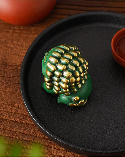 Rear view of a green Fortune Lion ornament with golden accents, displayed on a black tray, showcasing intricate mane details and traditional design elements.