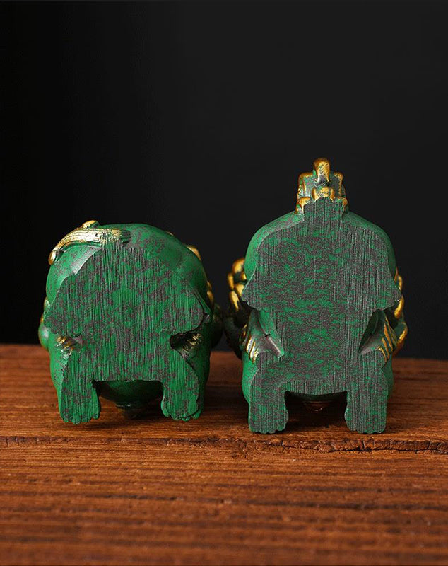 Bottom view of a pair of green mini stone lions with golden accents, showcasing the detailed base and craftsmanship, displayed on a wooden surface.