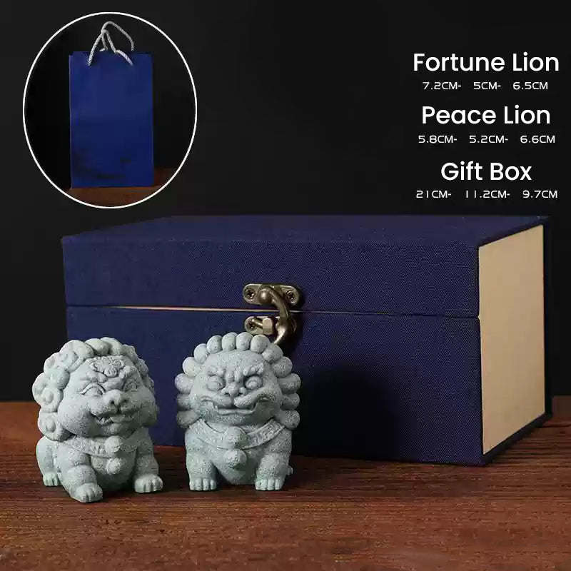 A pair of green sandstone mini stone lions, the Fortune Lion and Peace Lion, displayed in front of a navy blue gift box with a matching blue gift bag in the background, showcasing their dimensions as a thoughtful gift set for protection and prosperity.