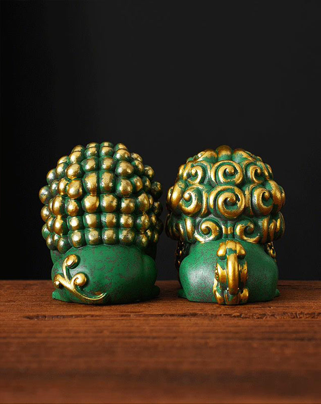 Rear view of a pair of green mini stone lions with golden accents, showcasing their intricately detailed manes and traditional craftsmanship, displayed on a wooden surface.