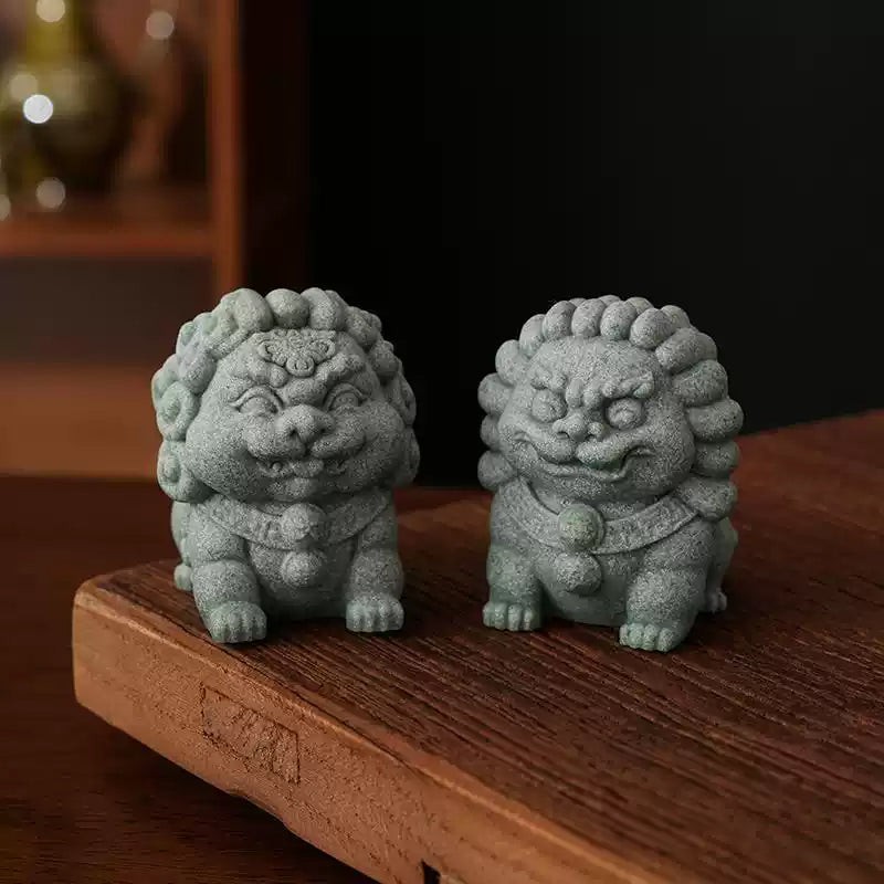 A pair of green sandstone mini stone lions, the Fortune Lion and Peace Lion, placed on a wooden platform with a traditional decor background, symbolizing protection and prosperity.