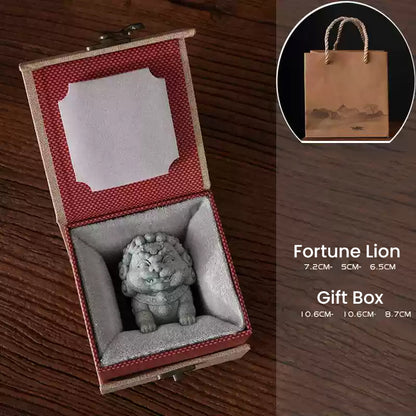 A Fortune Lion ornament made of green sandstone, elegantly placed in a red-lined gift box, alongside a paper bag with its dimensions noted, ideal as a thoughtful gift.