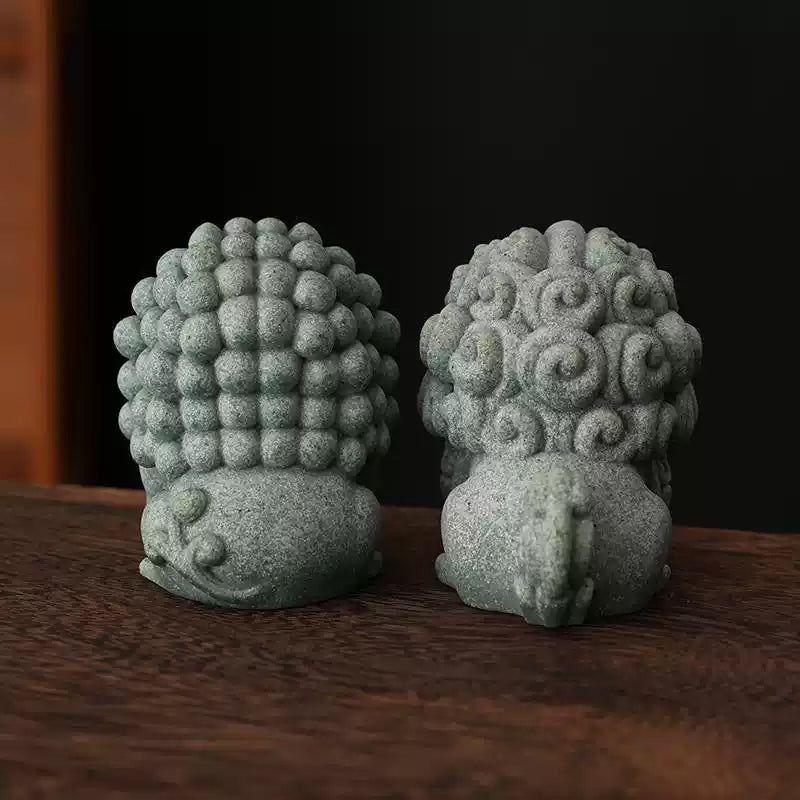 Rear view of a pair of green sandstone mini stone lions, showcasing intricate details of their curly manes and traditional craftsmanship, displayed on a wooden surface.