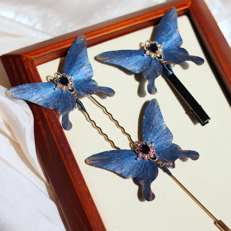 A stunning set of blue butterfly-themed hair accessories, including a hairpin, clip, and stick, adorned with intricate golden details and shimmering blue gemstones, handcrafted with care for a touch of elegance.