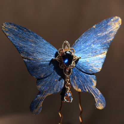 Handcrafted deep ocean blue velvet butterfly hairpin by Chujiu Mountain Atelier, adorned with golden accents, a teardrop-shaped blue crystal, and a dangling charm, inspired by the tranquility and elegance of the sea