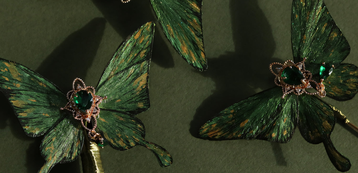 Close-up of Emerald Green Butterfly hair accessories featuring elegant green wings with golden accents and a heart-shaped green crystal set in a delicate golden frame, capturing the beauty of nature-inspired design.