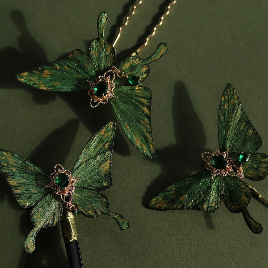 Collection of handcrafted emerald green velvet butterfly accessories by Chujiu Mountain Atelier, featuring golden accents, heart-shaped green crystals, and versatile designs including hairpins, clips, and brooches.