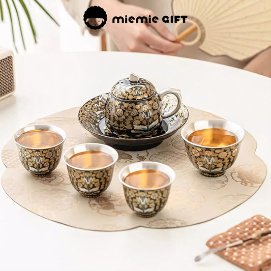 Golden Branches & Jade Leaves Gilded Silver Tea Set arranged for a tea ceremony, featuring a teapot and four cups on an elegant table mat, highlighting its intricate craftsmanship and cultural sophistication.