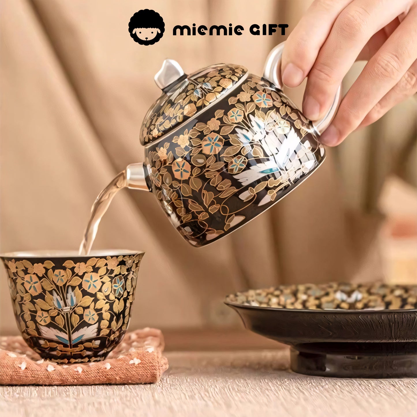 A close-up of the Golden Branches & Jade Leaves Gilded Silver Teapot pouring tea into a matching cup, showcasing the intricate gold floral design and elegant craftsmanship in action.