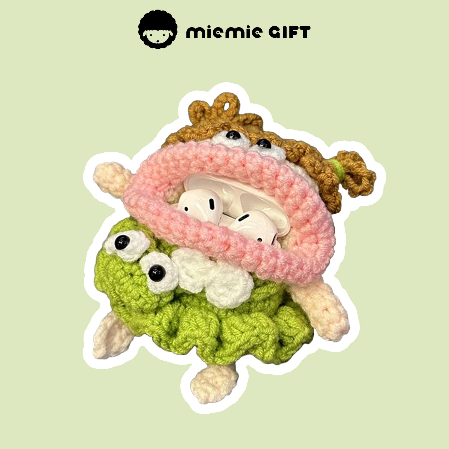 Handcrafted knit earphone case featuring a quirky design with a pink scarf and green skirt, showing AirPods stored inside. The case combines fun details and functionality, perfect for protecting your AirPods while giving them a unique touch.