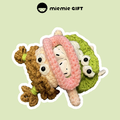 Handcrafted knit earphone case with a quirky design, showing curly brown hair, a pink scarf, and a green skirt. The case holds AirPods inside, providing a fun and unique way to store and protect your earphones.