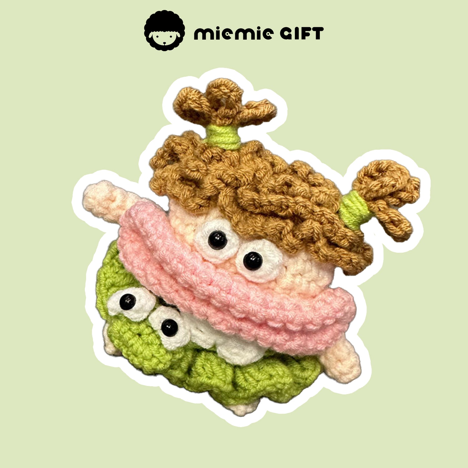 Close-up of handcrafted knit earphone case with a playful design of curly brown pigtails, a pink scarf, and a green skirt. The character features large eyes and a cute, whimsical look, designed to provide unique protection for your AirPods.