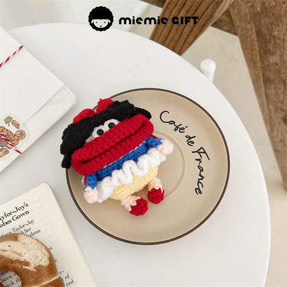 Handcrafted Snow White earphone case in vibrant colors (red, blue, yellow, and white) placed on a café plate. The playful design features black curly hair and a red bow, offering a fun, unique way to protect your AirPods.