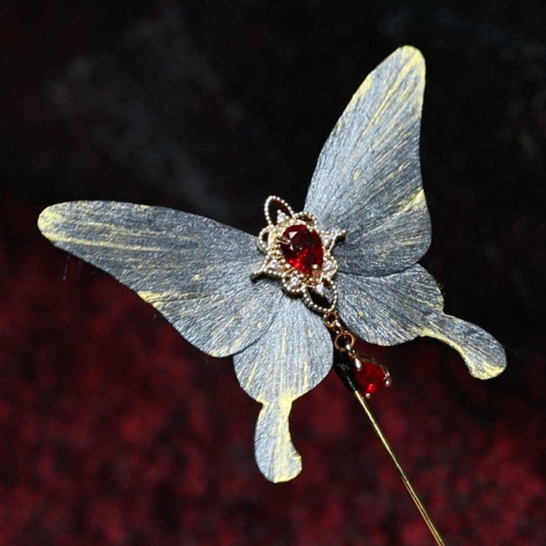 Handmade gray butterfly velvet flower hairpin featuring a striking red gemstone centerpiece, accented with gold detailing, showcasing exquisite traditional craftsmanship.