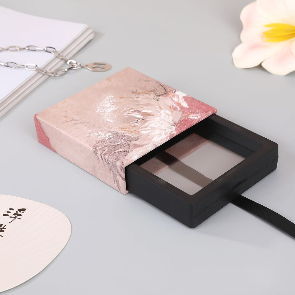 Elegant earphone case with a marble-patterned exterior in pink and gray tones, featuring a black frame and transparent window to show the earphone case inside.