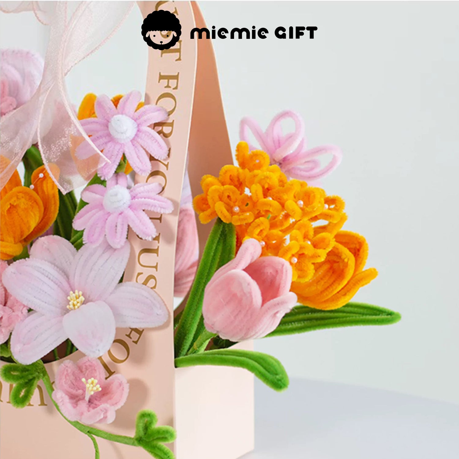 Close-up of MieMie Gift DIY Flower Basket showcasing vibrant orange handmade pipe cleaner flowers, paired with pink blooms for a lively design.

