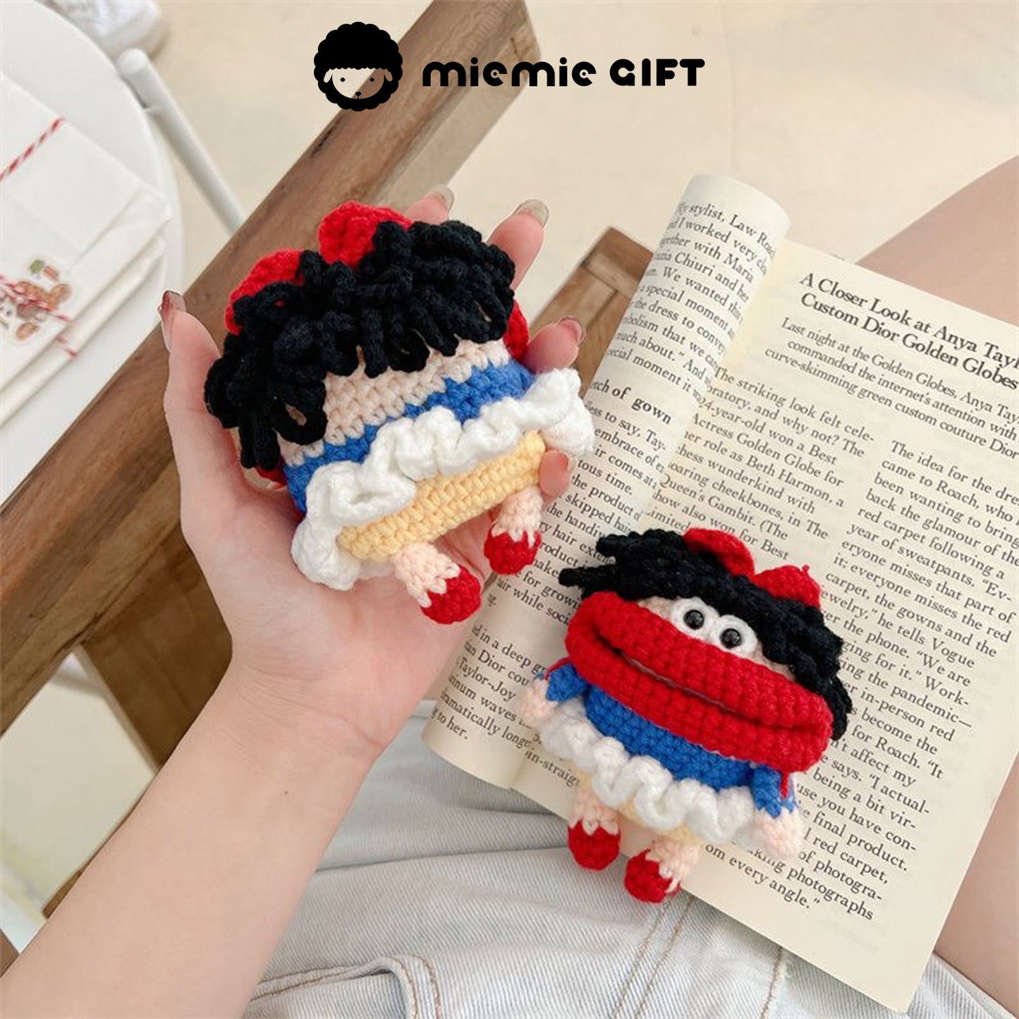 Hand holding the Snow White knit earphone case with AirPods inside. The case is colorful, featuring a red bow and black curls, offering a fun and functional design to protect your AirPods.