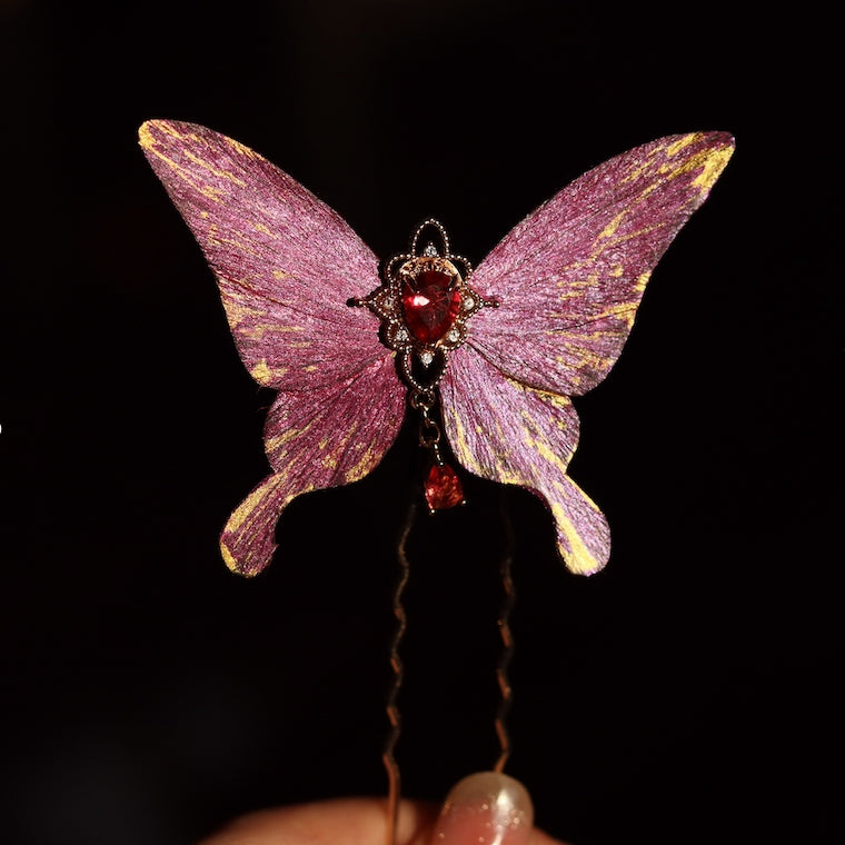 Exquisite royal purple velvet butterfly hairpin handcrafted by Chujiu Mountain Atelier, featuring golden accents, a vibrant red heart-shaped crystal, and a dangling charm for an elegant, luxurious style.






