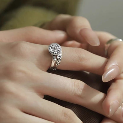 Elegant S925 sterling silver rotatable lotus ring with intricate design and dangling charm, worn gracefully on a finger for mindfulness and style.