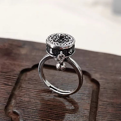 Stylish S925 sterling silver rotatable ring with intricate lotus design, engraved Six-Word Mantra symbols, and a dangling charm, placed on a wooden surface.