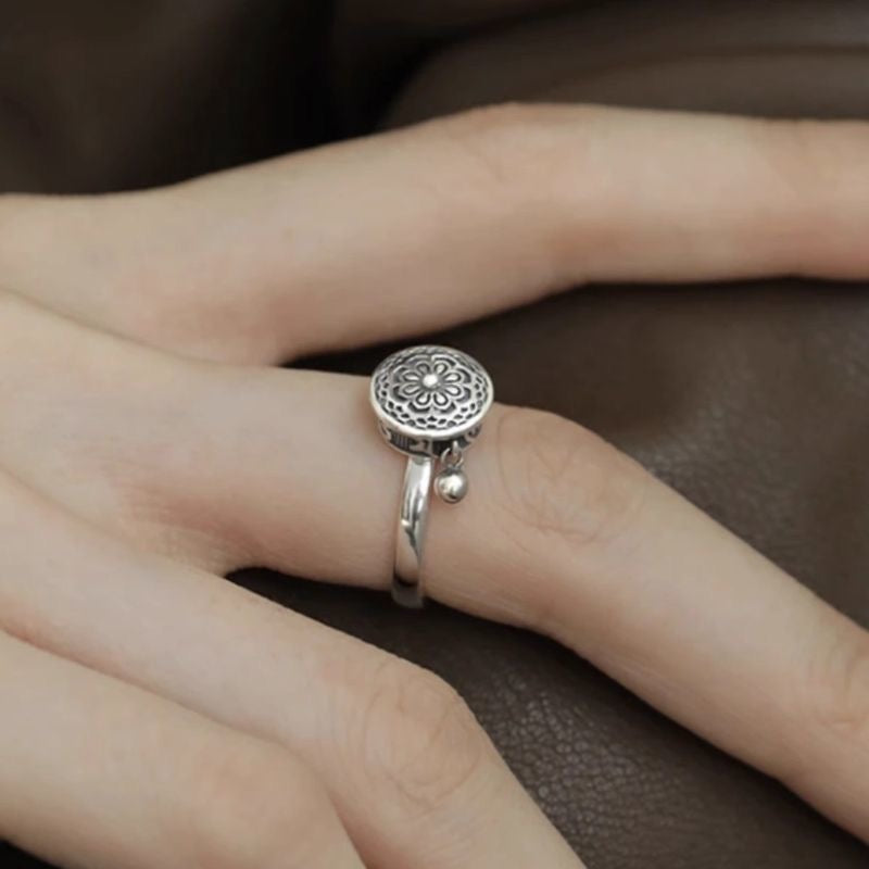 Stylish S925 sterling silver rotatable ring with intricate lotus flower design and dangling charm, elegantly worn on a finger, symbolizing mindfulness and good fortune.