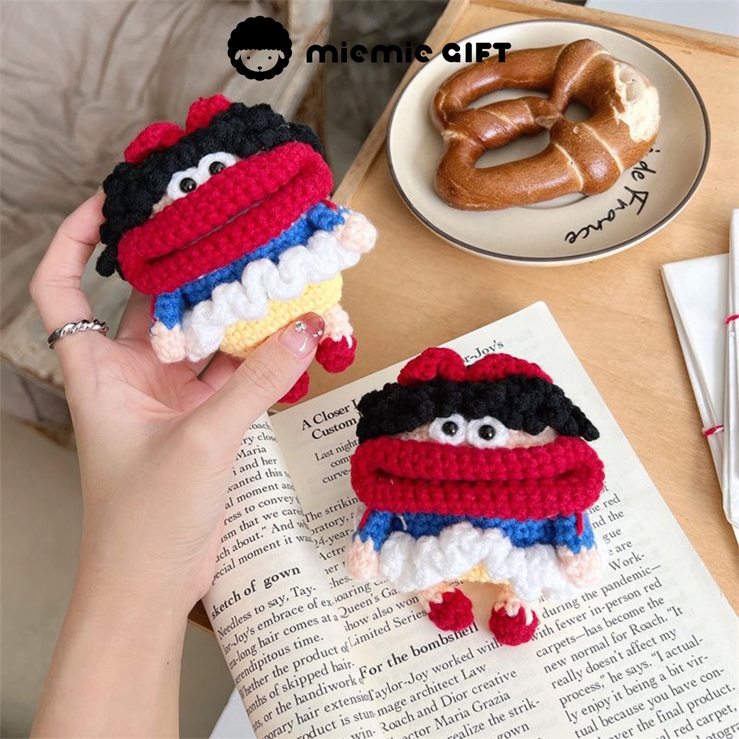 Hand holding the Snow White knit earphone case featuring a playful design in red, blue, yellow, and white, complete with black curly hair and a red bow. The case provides a cute and functional way to protect your AirPods.